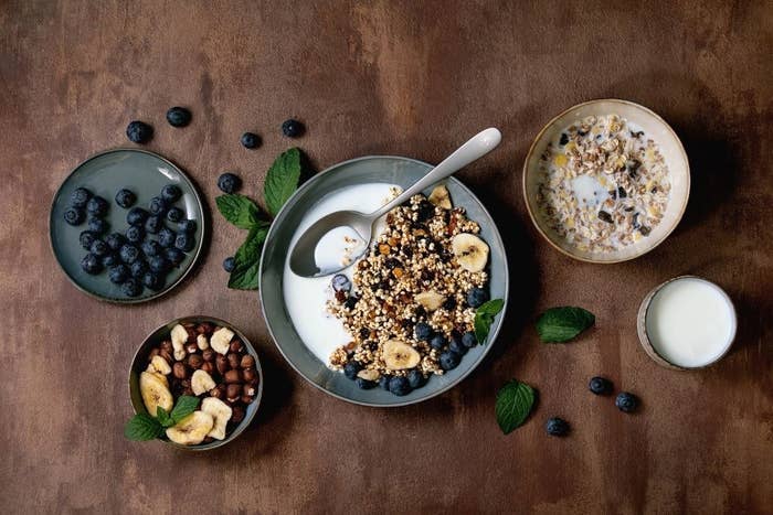 A bowl of cereal surrounded by toppings like dried fruit and berries.