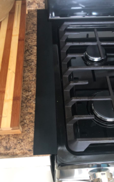 close up of the black strip on the edge of the stovetop that blends in with the black oven