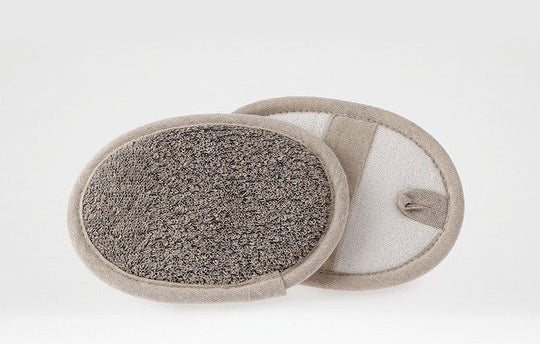 Oval skin cleaning mitt with scrubbing side and strap for hand, including a loop for hanging storage