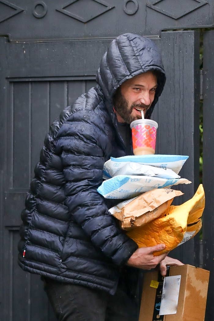 Ben Affleck smiles as he sips on his iced coffee and balances the packages