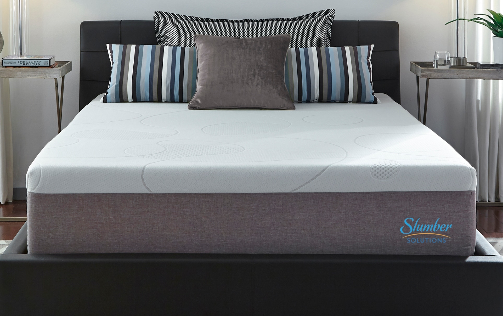 A mattress sitting on a bed frame. There are pillows on top of the mattress. 