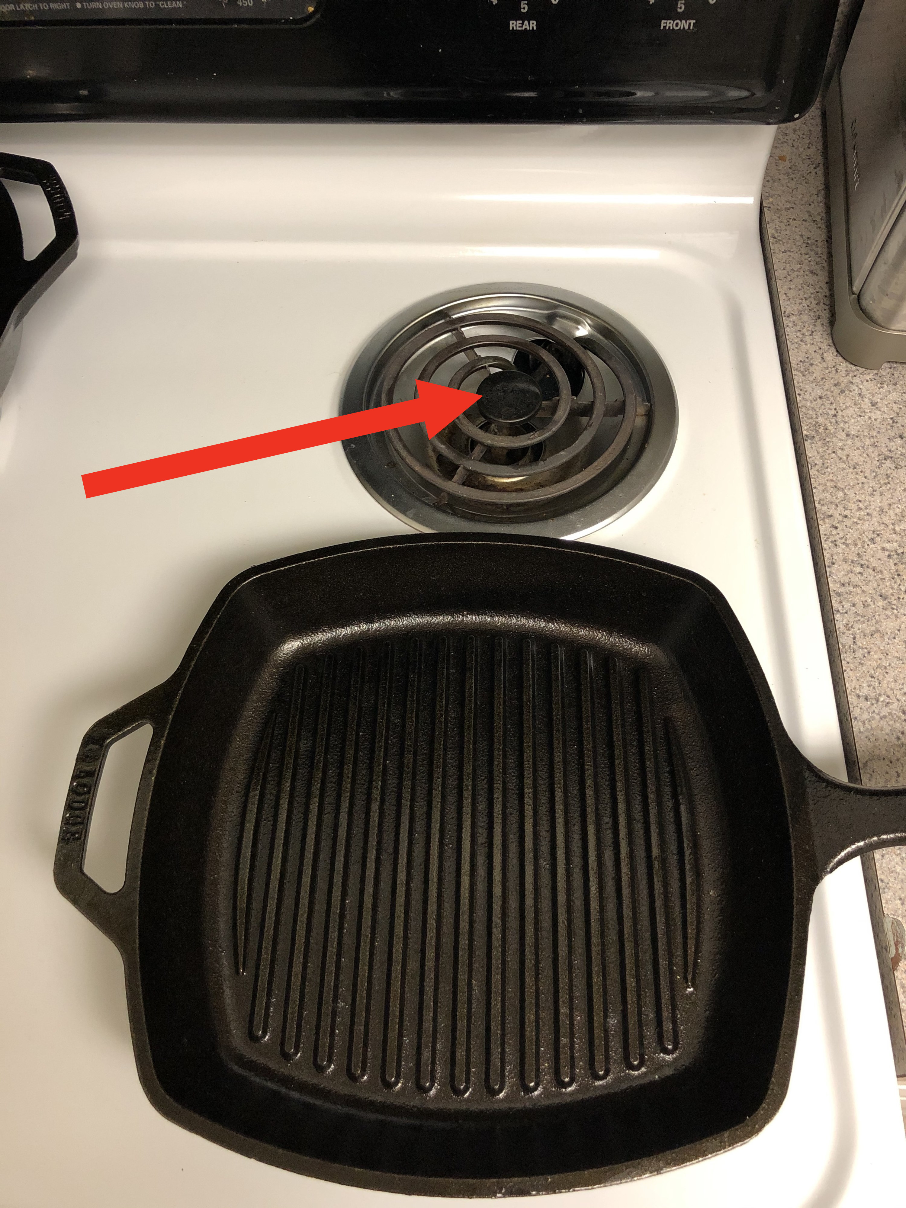 An overhead shot of an electric stove, with an arrow pointing at the back burner