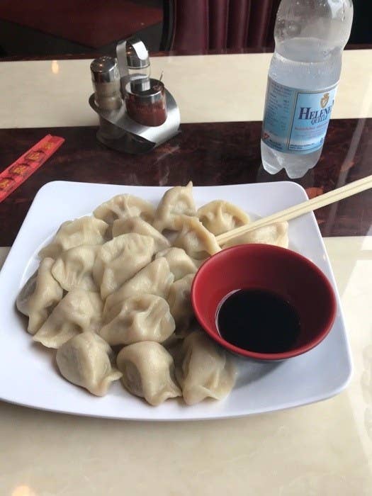  A plate holds a huge pile of dumplings and a small bowl of sauce