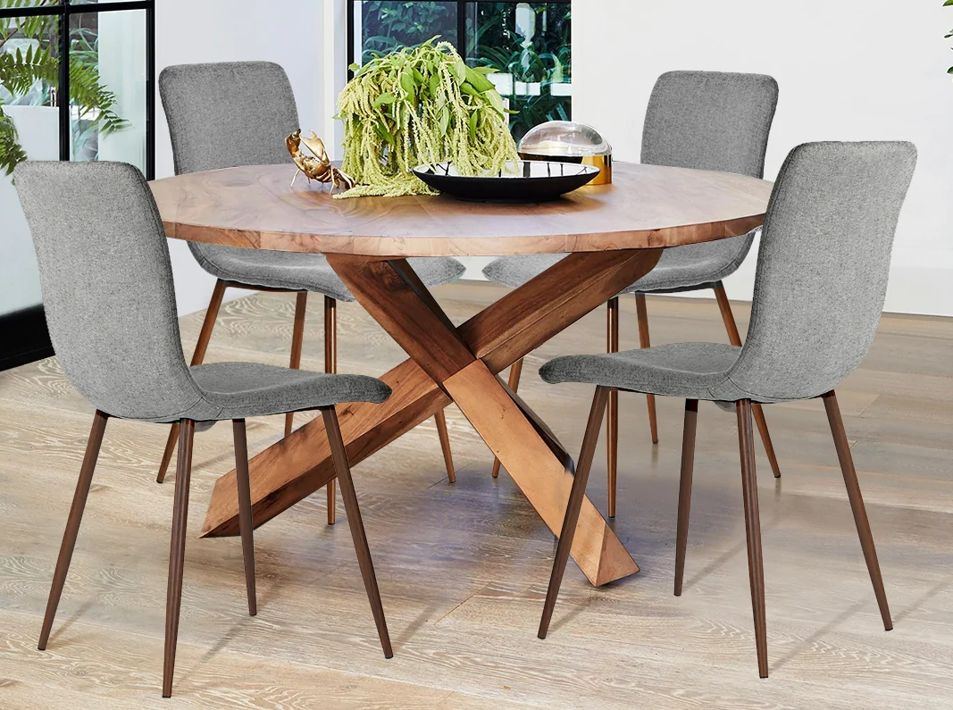 Four dining chairs around a wooden, circular dining table. There is a plant on the table. 
