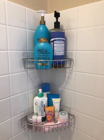 A reviewer's photo of the silver caddies holding body wash, shampoo, and other products