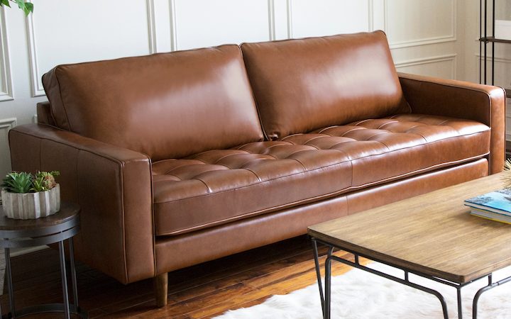 A brown leather sofa sitting in a living room.