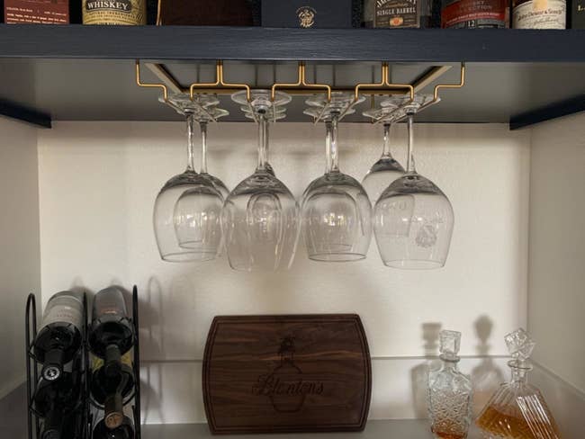 A reviewer's photo of a gold stemware organizer holding eight wine glasses