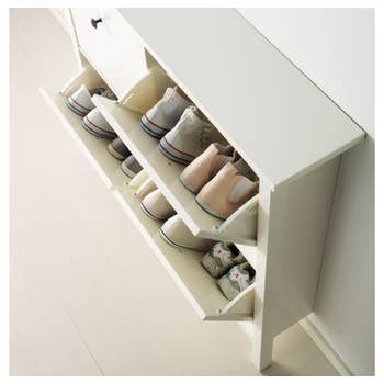 The white cabinet with two drawers open revealing shoes