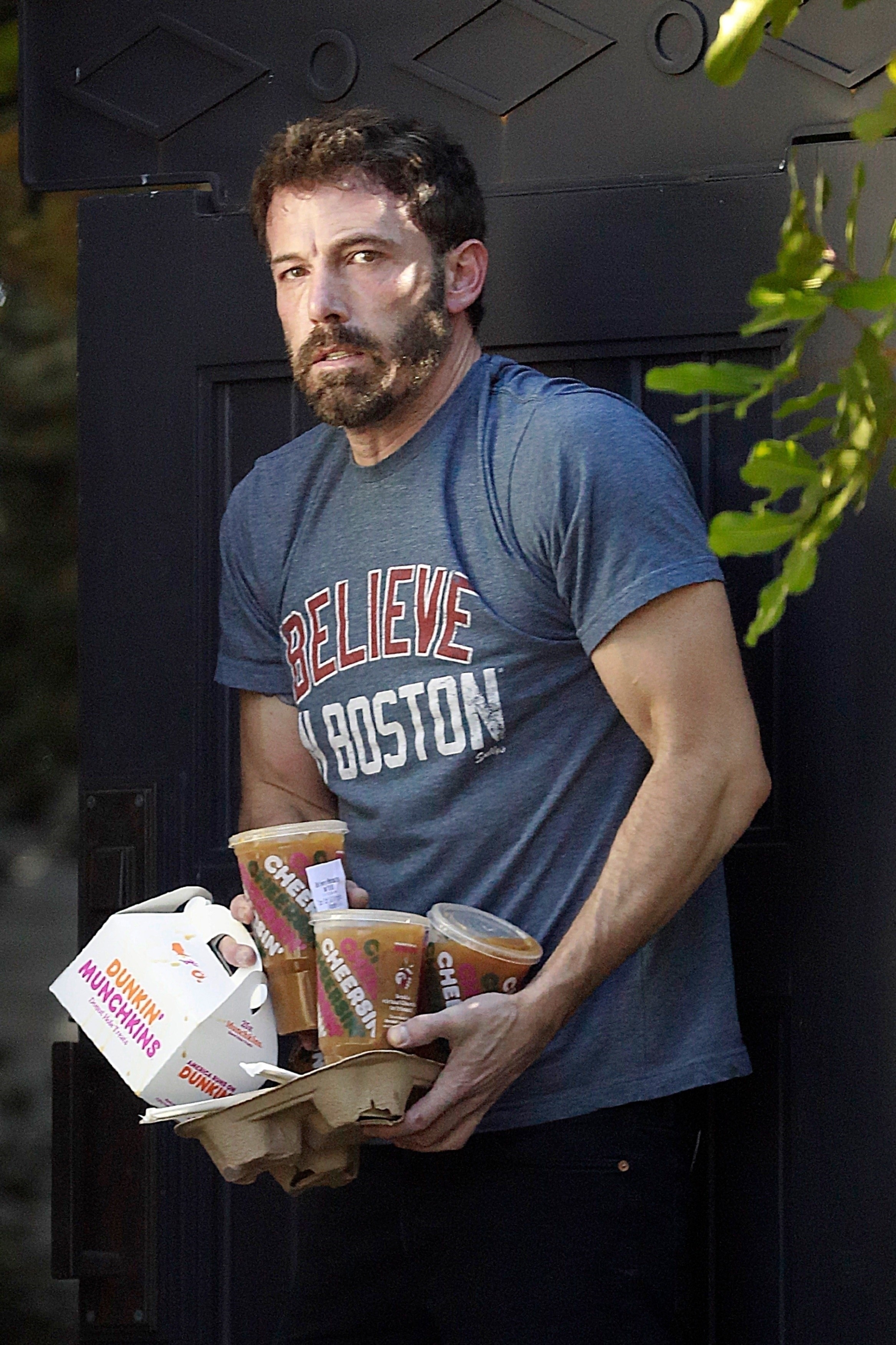 Ben Affleck, on another day, balances several iced coffees and a box of donut holes