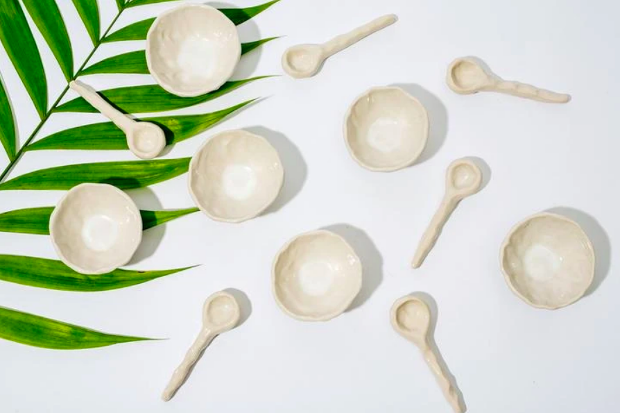 Several small pinch pots and spoons on a leafy table
