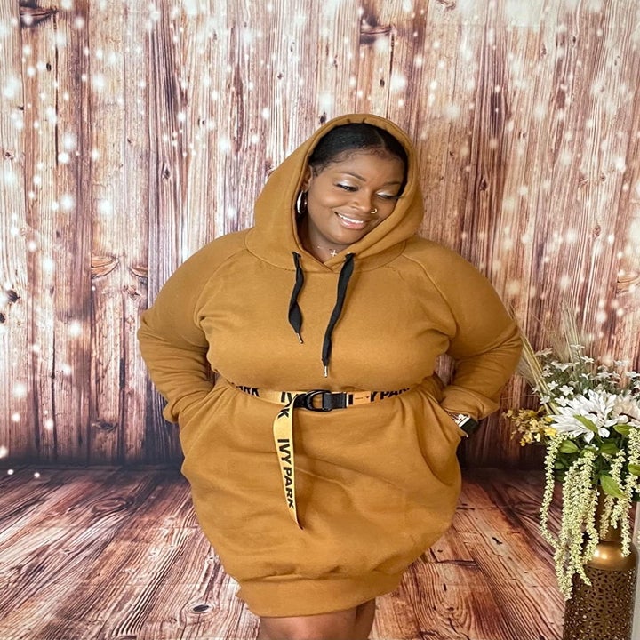 Reviewer wears mustard yellow hoodie dress with Ivy Park belt while relaxing at home