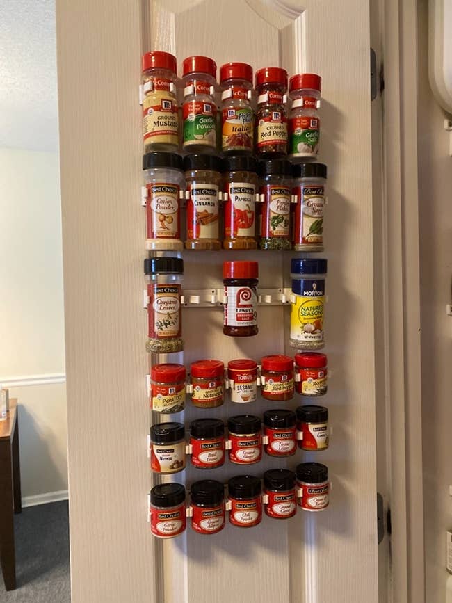 A reviewer's white rack with a bunch of spices used on the inside of a closet door