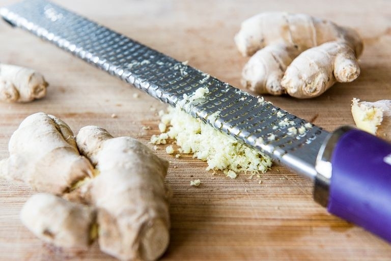 Fresh ginger being grated on a microplane