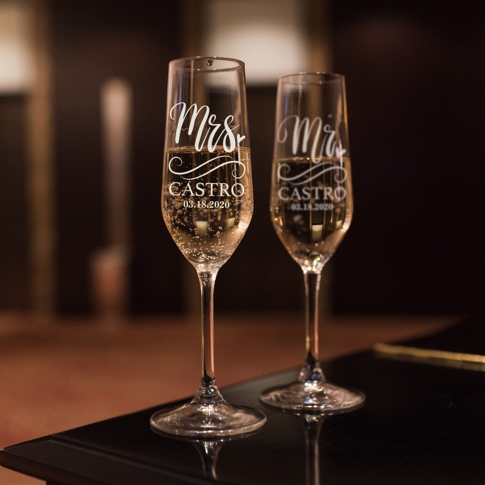 Champagne glasses customized with the words &quot;Mr.&quot; and &quot;Mrs.&quot; with the couple&#x27;s name written in cursive.