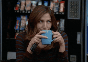 A woman holding a cup of coffee rolling her eyes 
