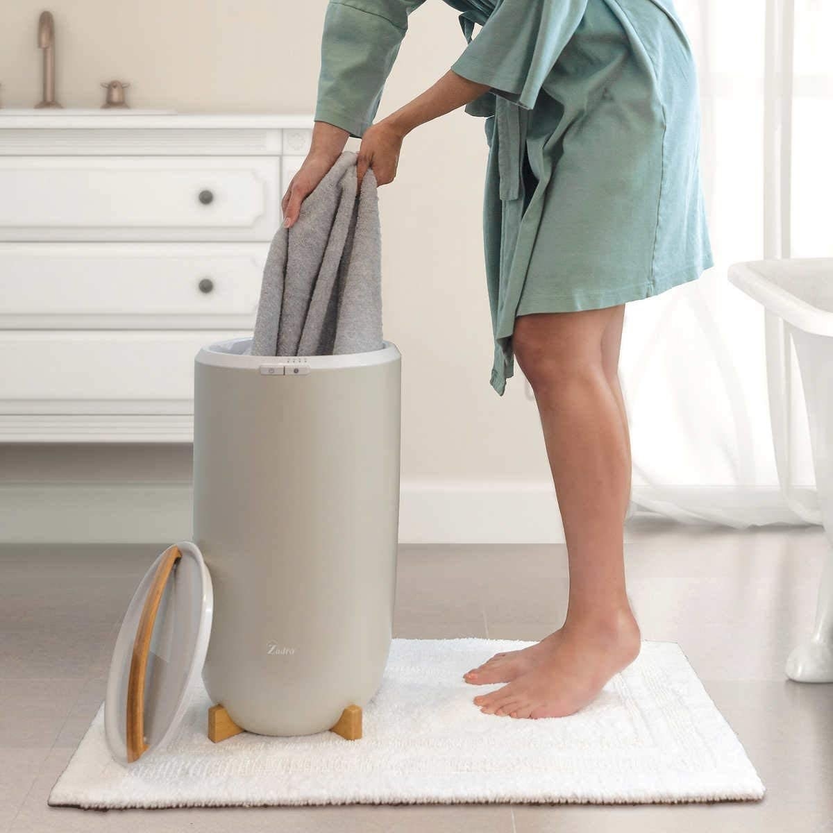 The circular-shaped bin in grey with a lid and wood handle
