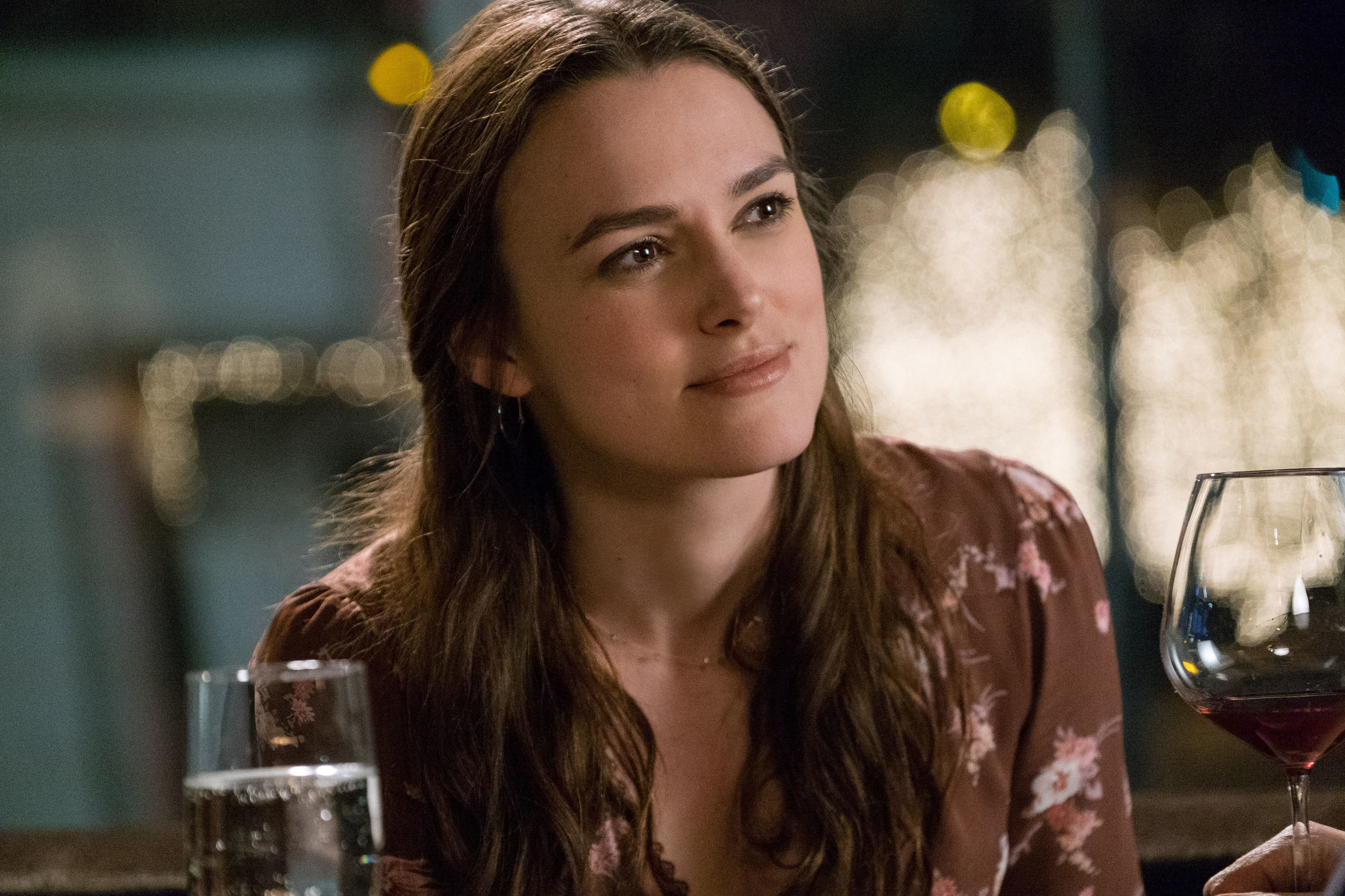 Keira Knightley sits in front of two glasses in the 2016 film Collateral Beauty