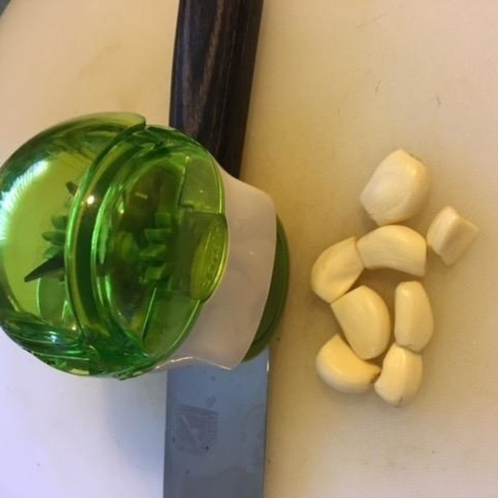 reviewer photo showing the garlic mincer next to several cloves of garlic 