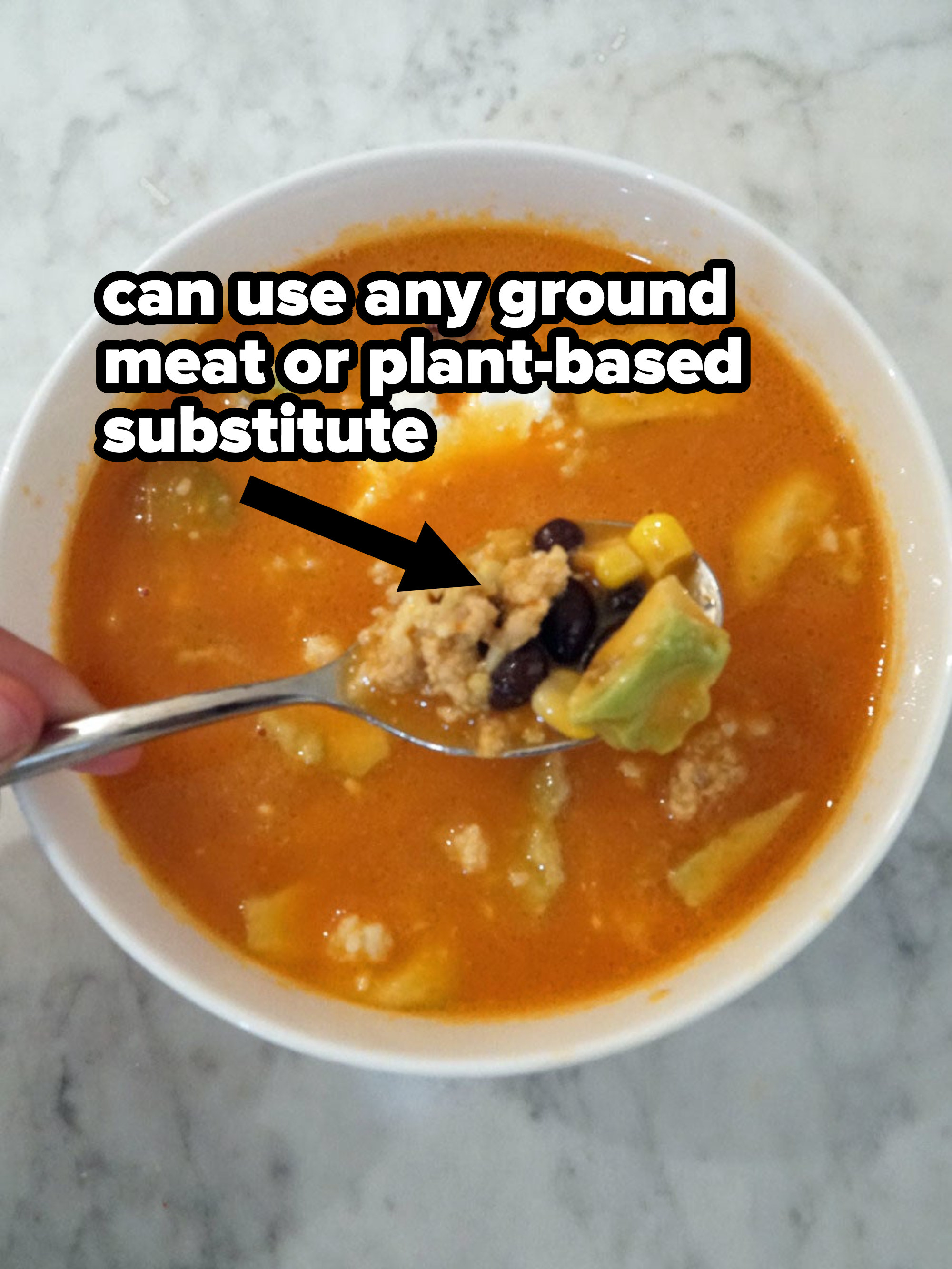A scoop of tomato soup with beans, corn, ground chicken, and avocado.