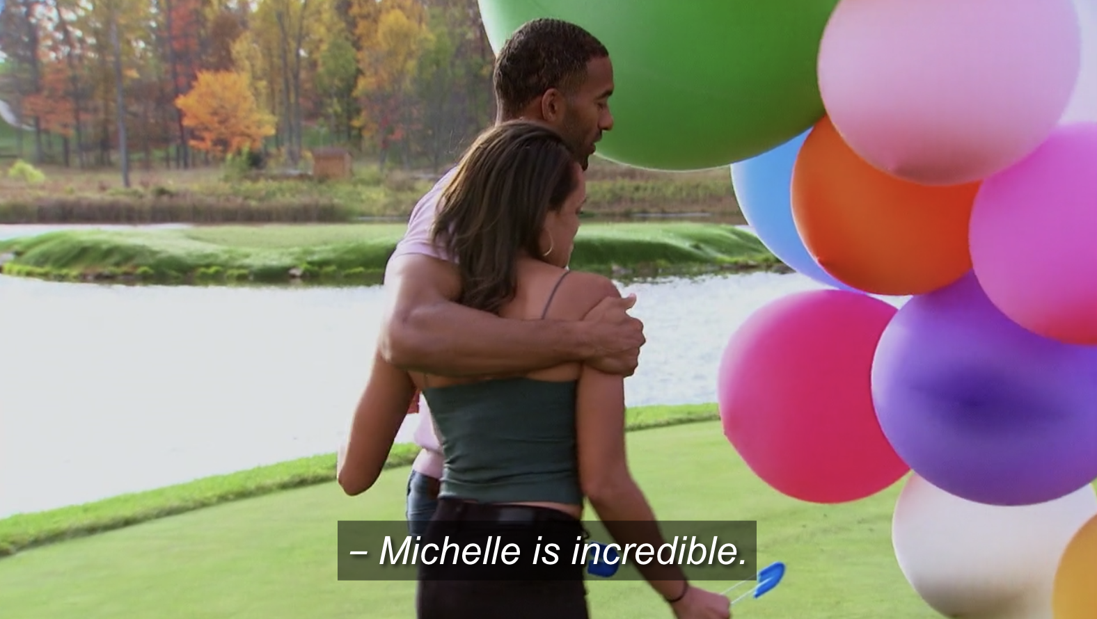 Michelle and Matt James hugging in front of a bouquet of balloons 