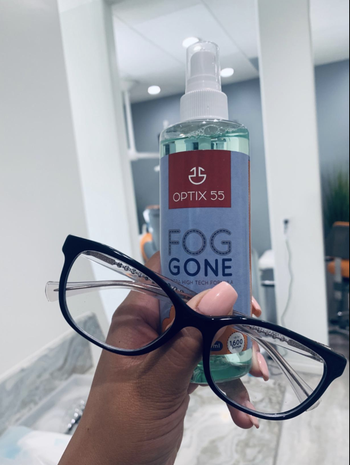 reviewer holding up glasses next to bottle of fog gone 