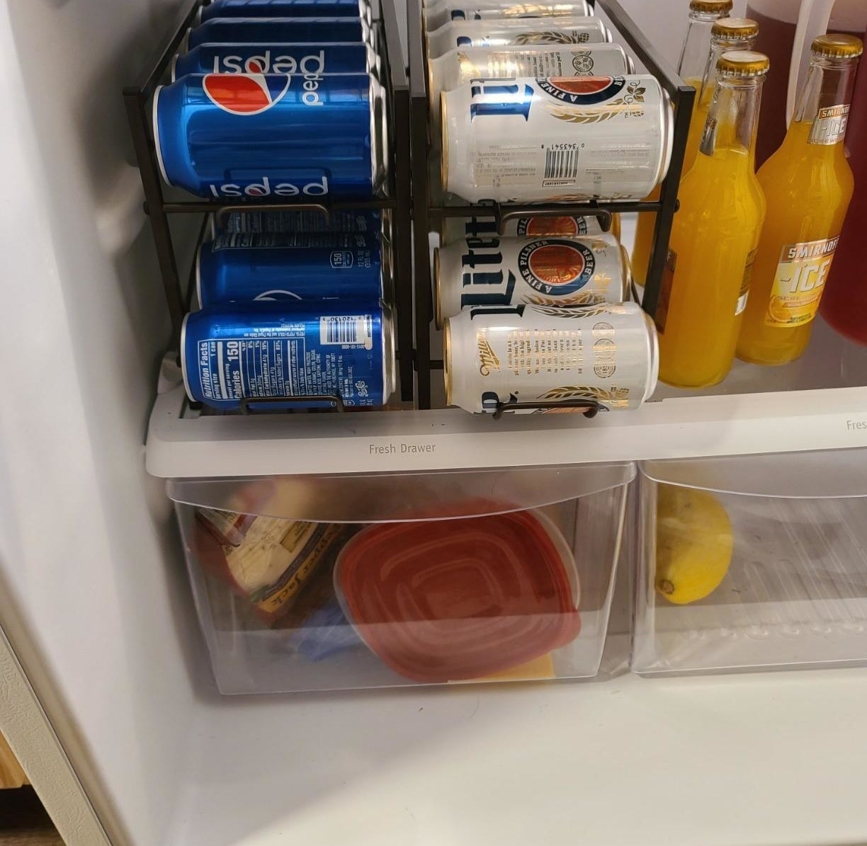 reviewer image of soda and beer cans organized on two soda can racks in a customer&#x27;s fridge