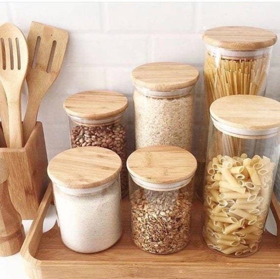 Six of the bamboo and glass jars filled with pasta, rice, beans, and oats