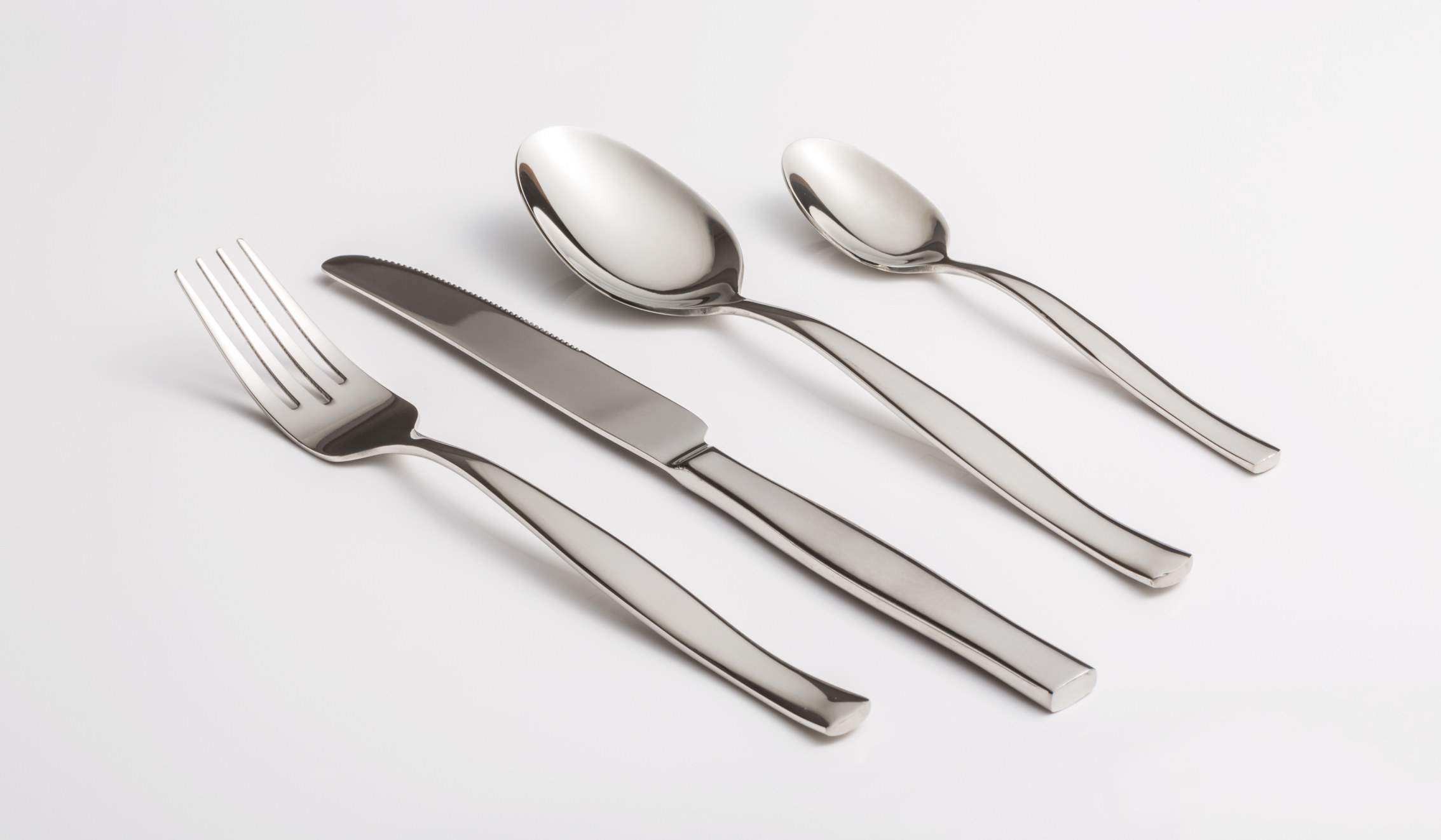 Set of utensils, featuring a fork, knife, and two spoons, on a table