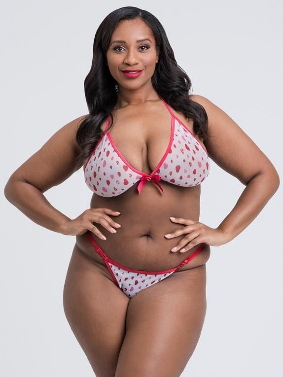 a model wearing a white bra with red accents, a red bow in the middle, tiny pink and red hearts throughout with a matching thong