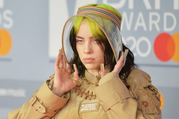 Billie Eilish posing at the Brit Awards 2020 wearing a Burberry London coat, a clear visor, and long nails featuring the Burberry&#x27;s signature and iconic tartan print 