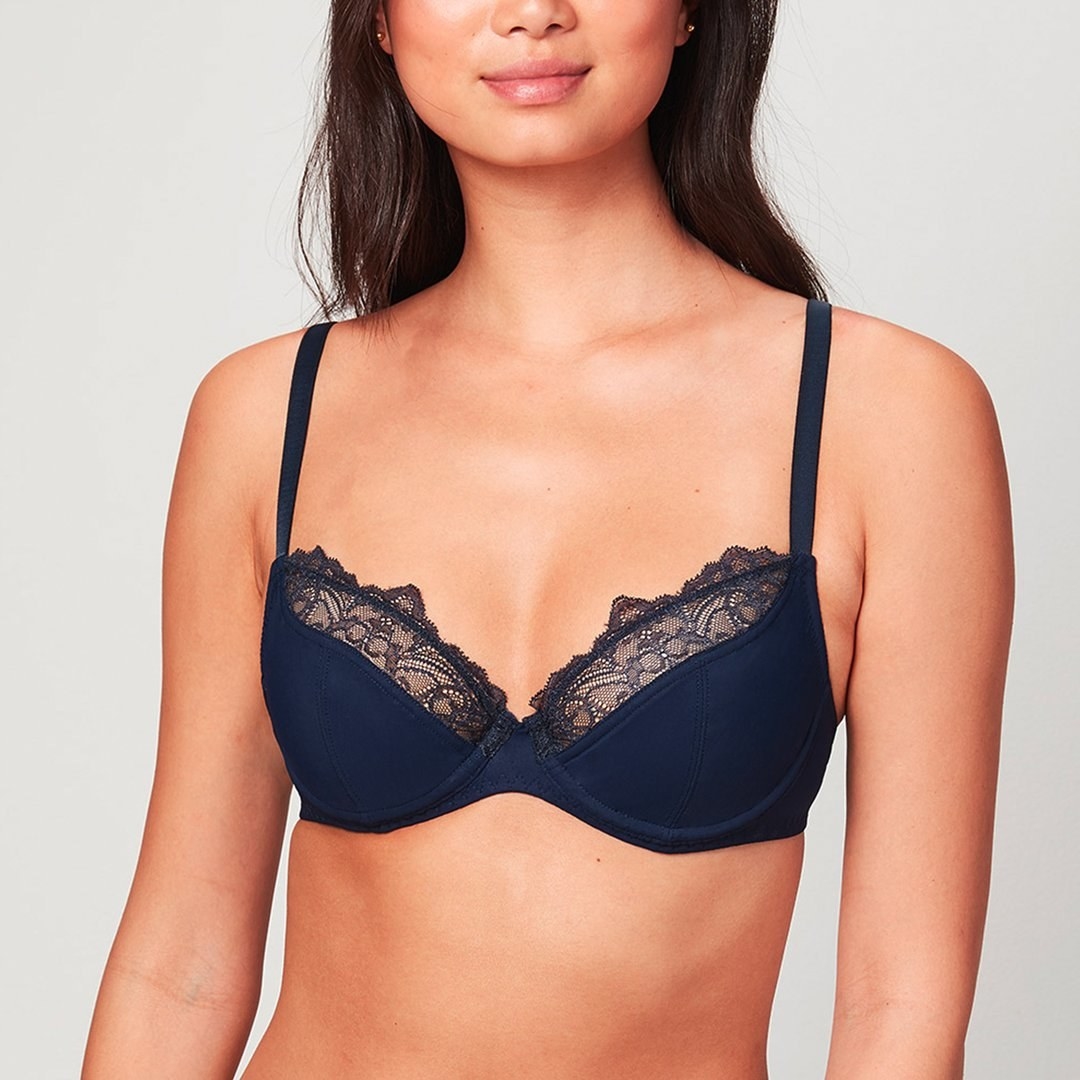 a model in a navy blue bra with lace at the top of the cups