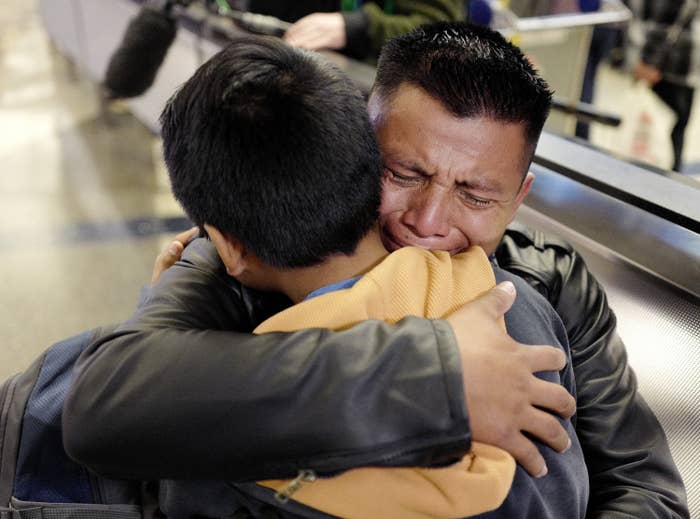 A crying father and son hug