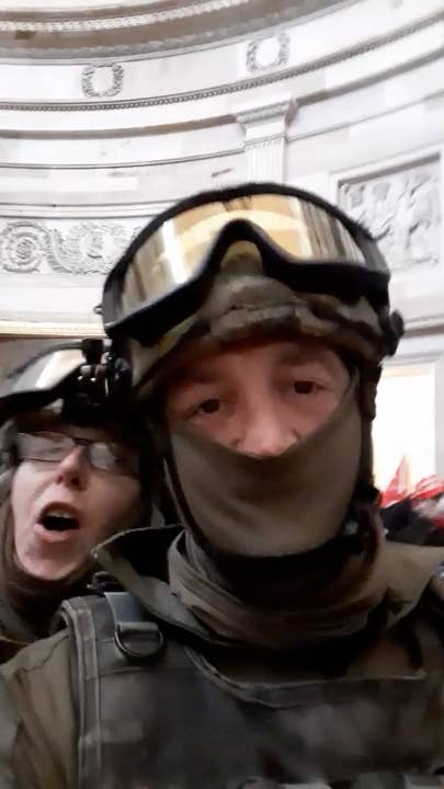 Two people, wearing military-style gear, including face coverings and goggles, take a blurry selfie