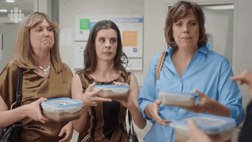 Three women handing back containers of meal-prepped food shaking their heads no
