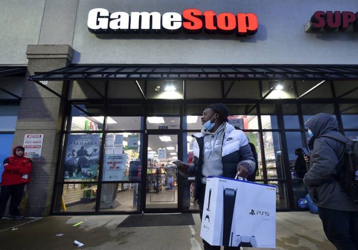 A man wearing a face mask leaves a Game Stop store with a PlayStation 5 box