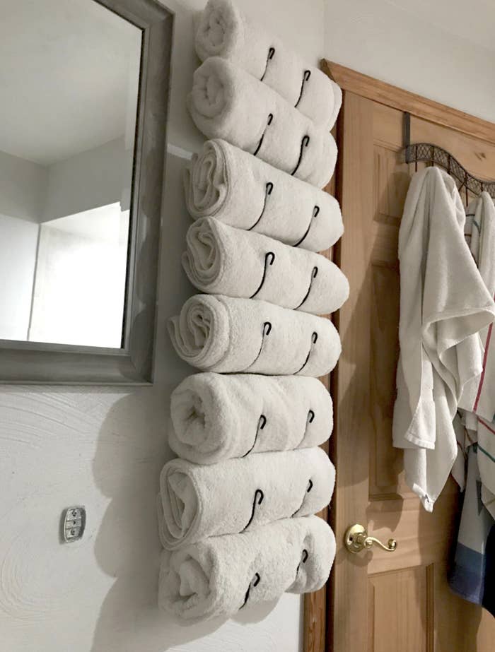reviewer image or rack installed in bathroom holding tons of rolled towels