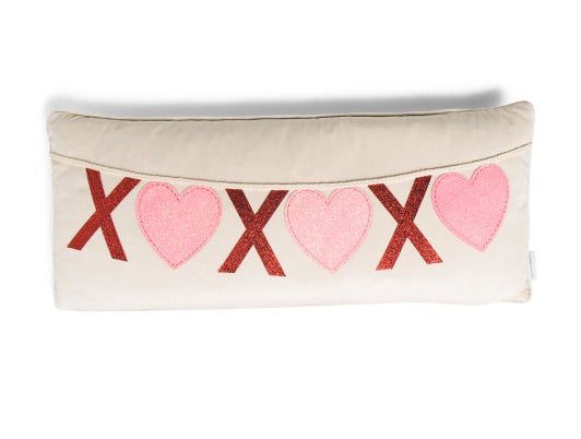 a tan lumbar pillow with an "xoxo" designed banner across it