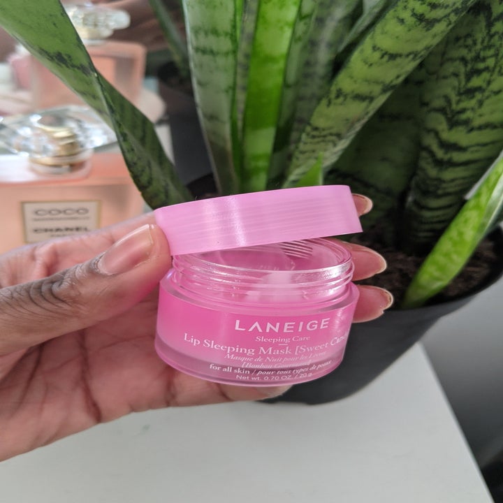A person holding a small jar with a lip mask inside