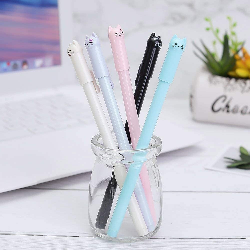 Pens in white, purple, pink, blue, and black with little cats on the lids 