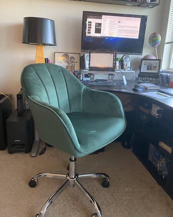 Reviewer image of green velvet swivel arm chair with thin arm rests in front of desk 