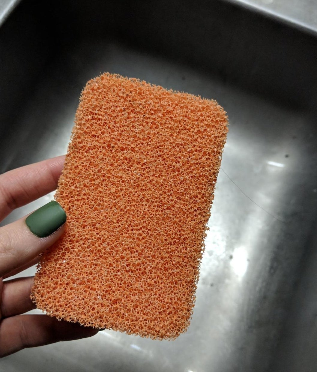 Reviewer holding silicone sponge over sink