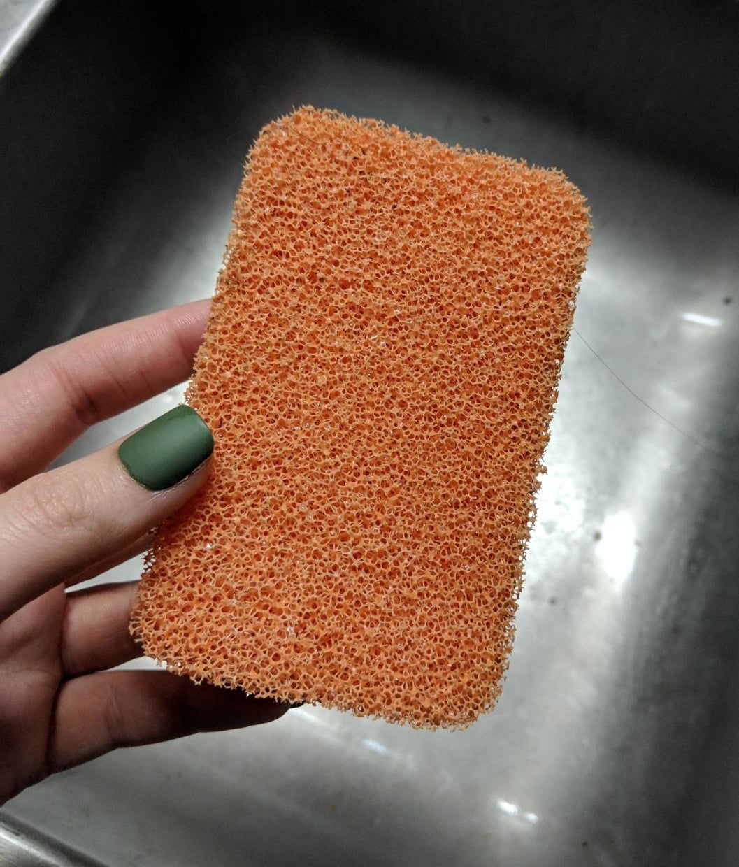 Reviewer holding silicone sponge over sink