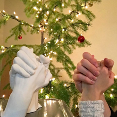 Couple holding hands beside matching mold of their hands made from kit