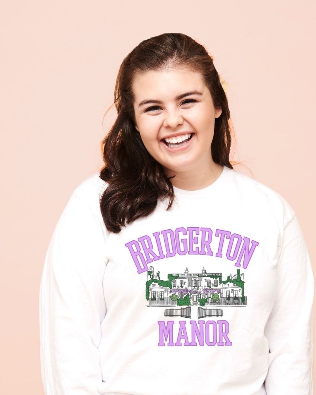 a model in a white long sleeve with an illustration of bridgerton manor on it
