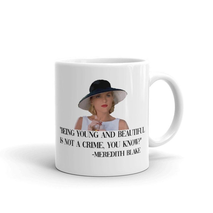 a white mug with meredith blake on it that says "being young and beautiful is not a crime you know"