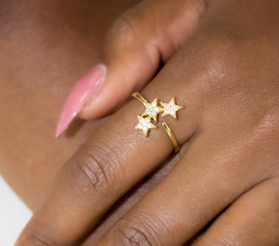 the gold ring with three little stars on it on a person&#x27;s finger
