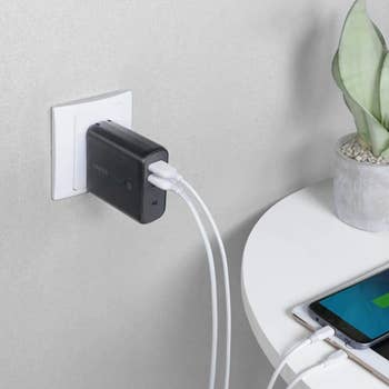 Anker PowerCore Fusion plugged into wall outlet with two USB charging cables connected