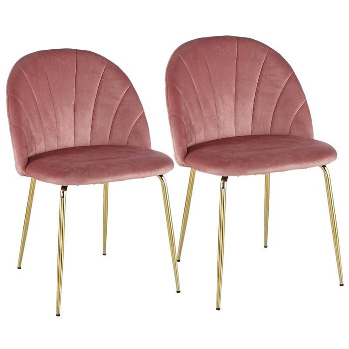 Two rose pink velvet chairs with rounded backs, scalloped seams, and gold legs
