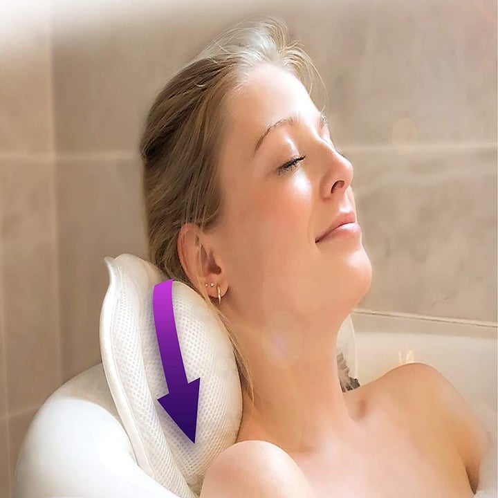 A person with their head on the pillow in the bathtub.