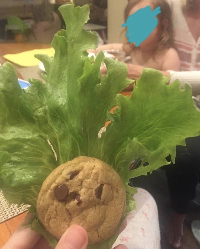 Person hiding a cookie behind a piece of lettuce